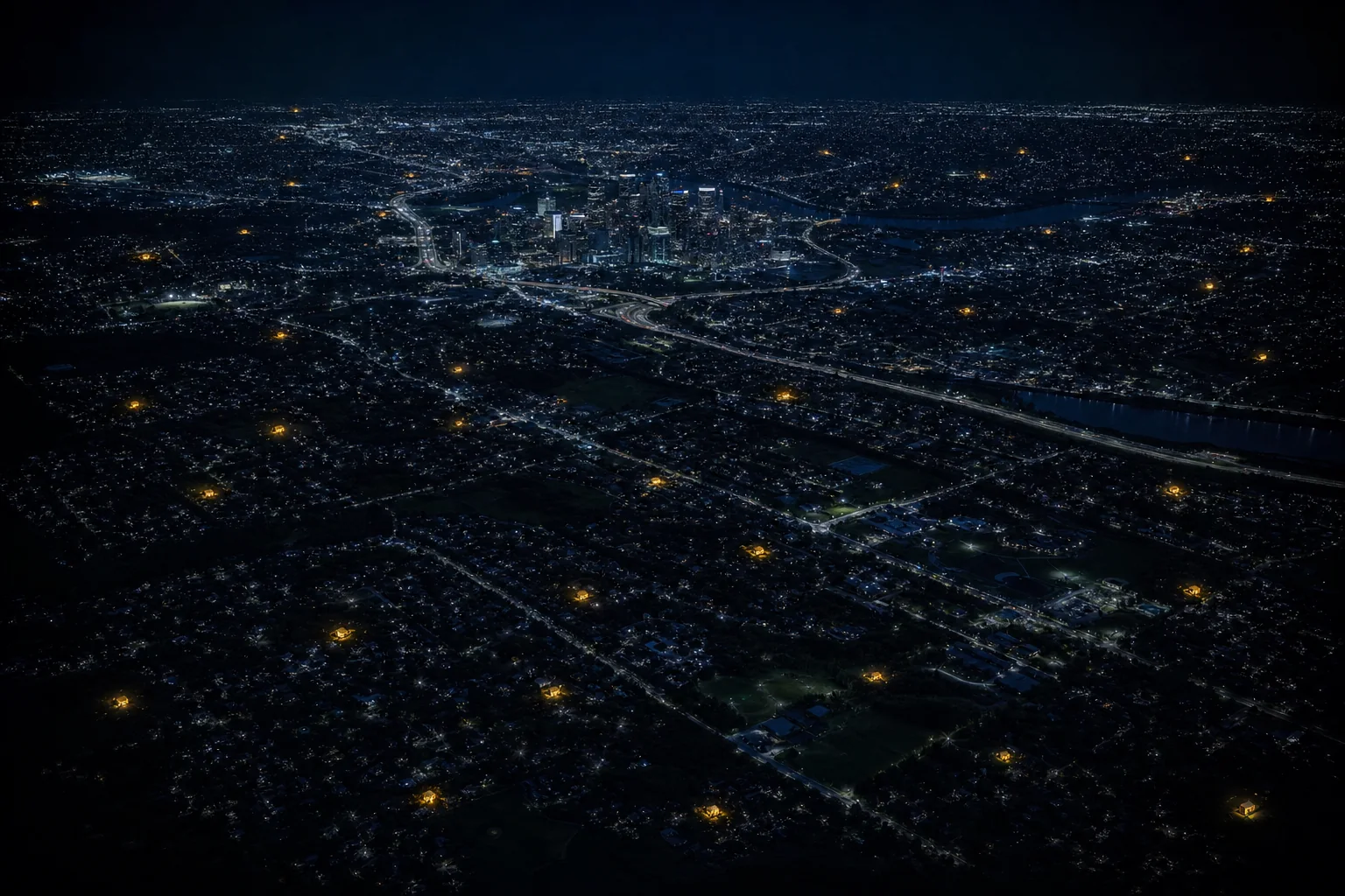 A city at night from above, with thirty homes miles apart lit gold