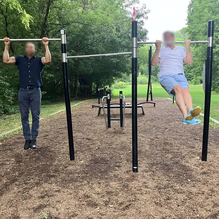 Two members doing pull-ups in a park
