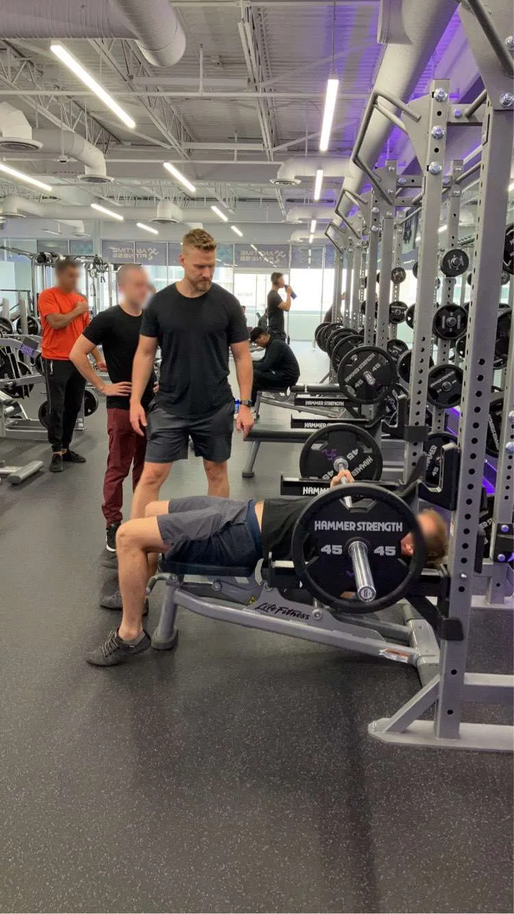 Trav spotting a member on the bench press at the gym